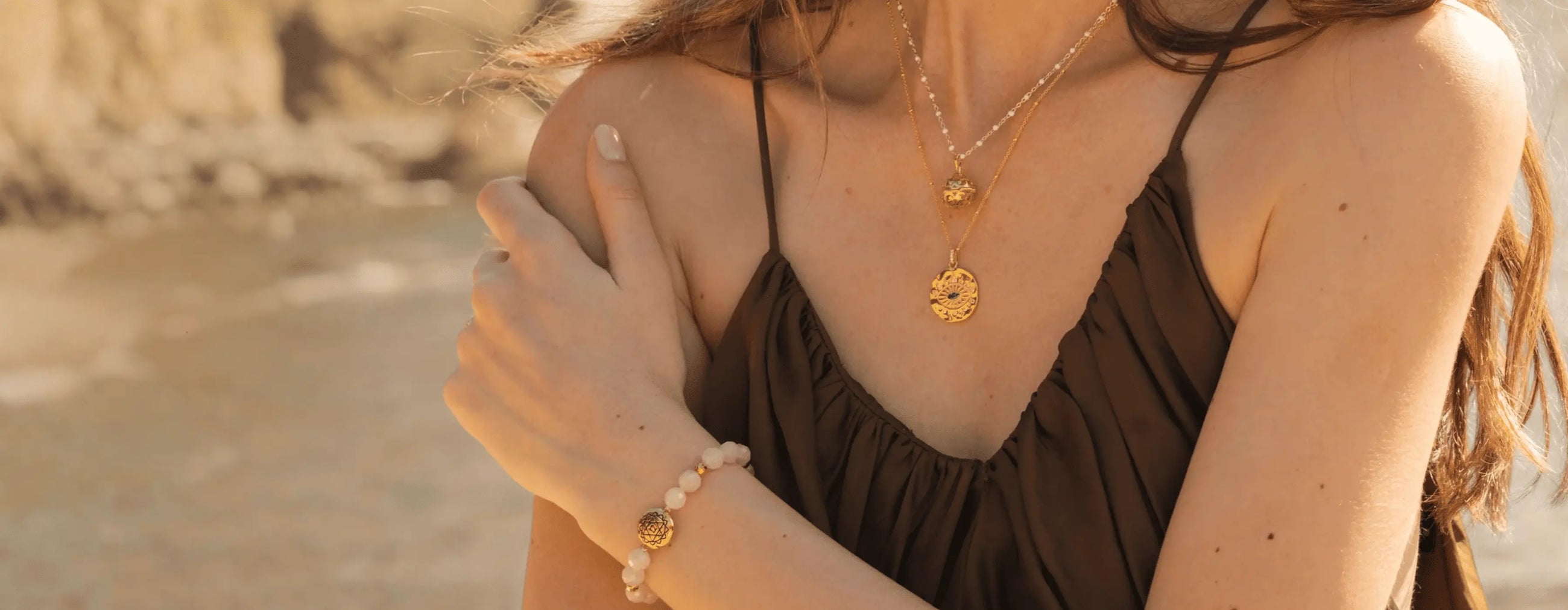 Woman wearing a brown dress with gold jewelry on a beach