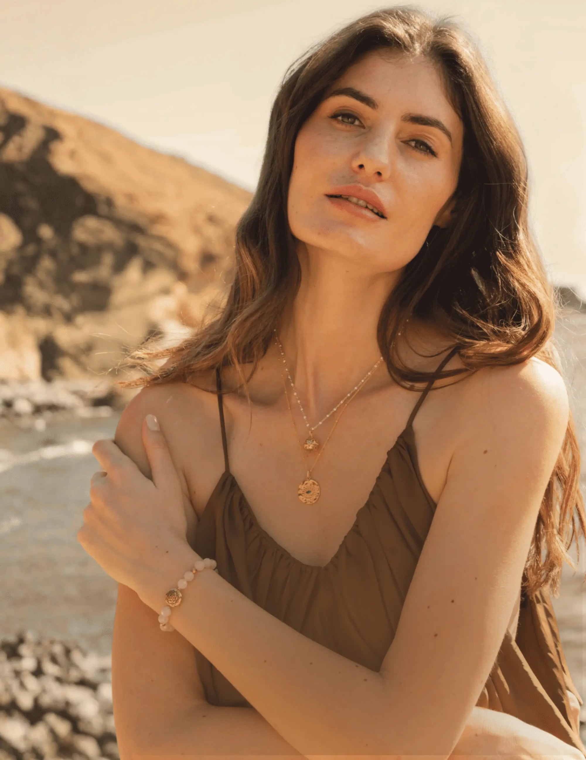 Woman sitting on a beach with mountains in the background